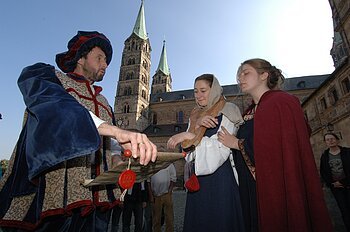 Spannend und anschaulich sucht diese Führung für Jugendliche wichtige Bauwerke und Denkmäler in chronologischer Reihenfolge auf. Sie führt aus der Zeit des Mittelalters in Renaissance, Barock und Neuzeit. Immer wieder schlüpft der Führer in die Rolle eines Betroffenen und erzählt von den Ereignissen seiner Zeit. Der Weg durch Bamberg wird zu einem Gang durch 1000 Jahre - so wird der Lauf der Geschichte spürbar! Für die Teilnehmer besteht die Möglichkeit, ihr Wissen aus dem Geschichts- und Kunstunterricht spielerisch zu wiederholen und zu überprüfen. Die Gelegenheit zu eigenen praktischen Übungen bereichert die Führung zusätzlich.